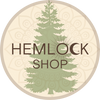 The company's name, HEMLOCK SHOP, in brown letters lays over a green tree in the middle of a circular, brown and beige dreamcatcher.